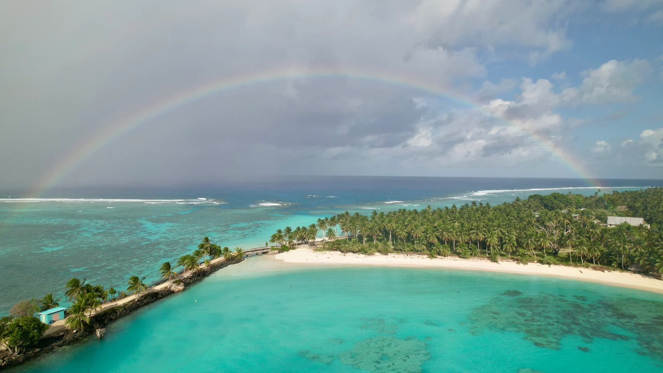 Aerial lagoon with rainbow over reef by Croome Photography